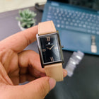Franklord Dusky Royale watch held in hand, showing side view of glossy black rectangular dial and beige strap