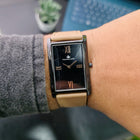 Franklord Dusky Royale rectangular watch with black dial and beige strap on wrist, front angle