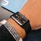 Close-up of Franklord Noir Luxe rectangular black dial watch held in hand