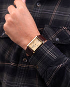Close-up of Franklord Royal Gold Heritage rectangular gold watch on wrist with brown strap
