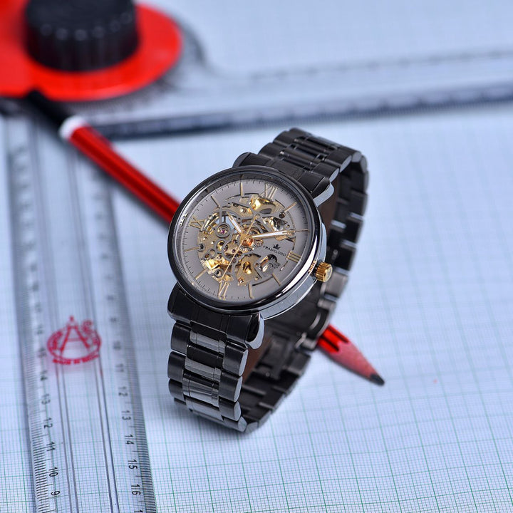 Franklord Titanium Shadow Watch upright on graph paper, with a red pencil, emphasizing its premium skeleton design and gold-accented details.